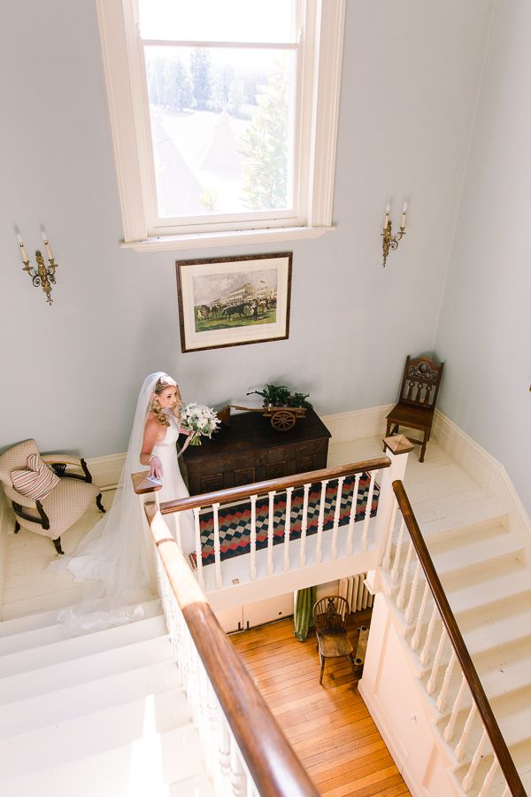 White staircase with wooden railing and hardwood floors in a bright interior space with natural lighting.