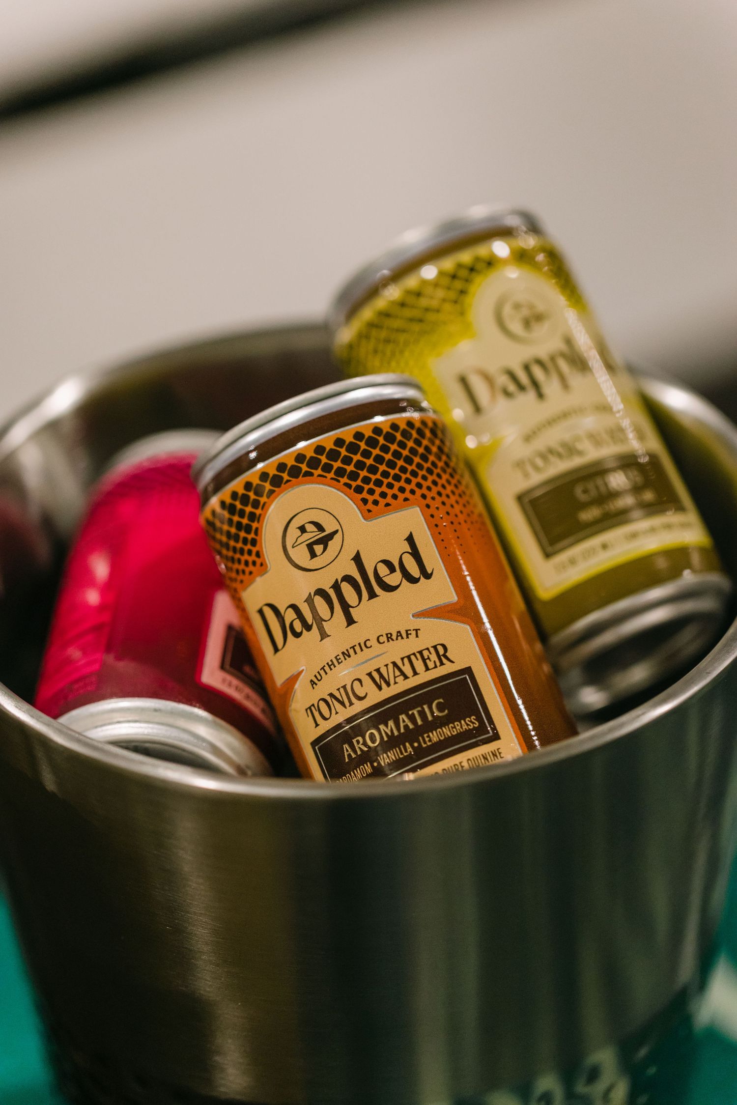 Dappled Authentic Craft Tonic Water cans in a metal ice bucket, featuring Aromatic and Citrus varieties.