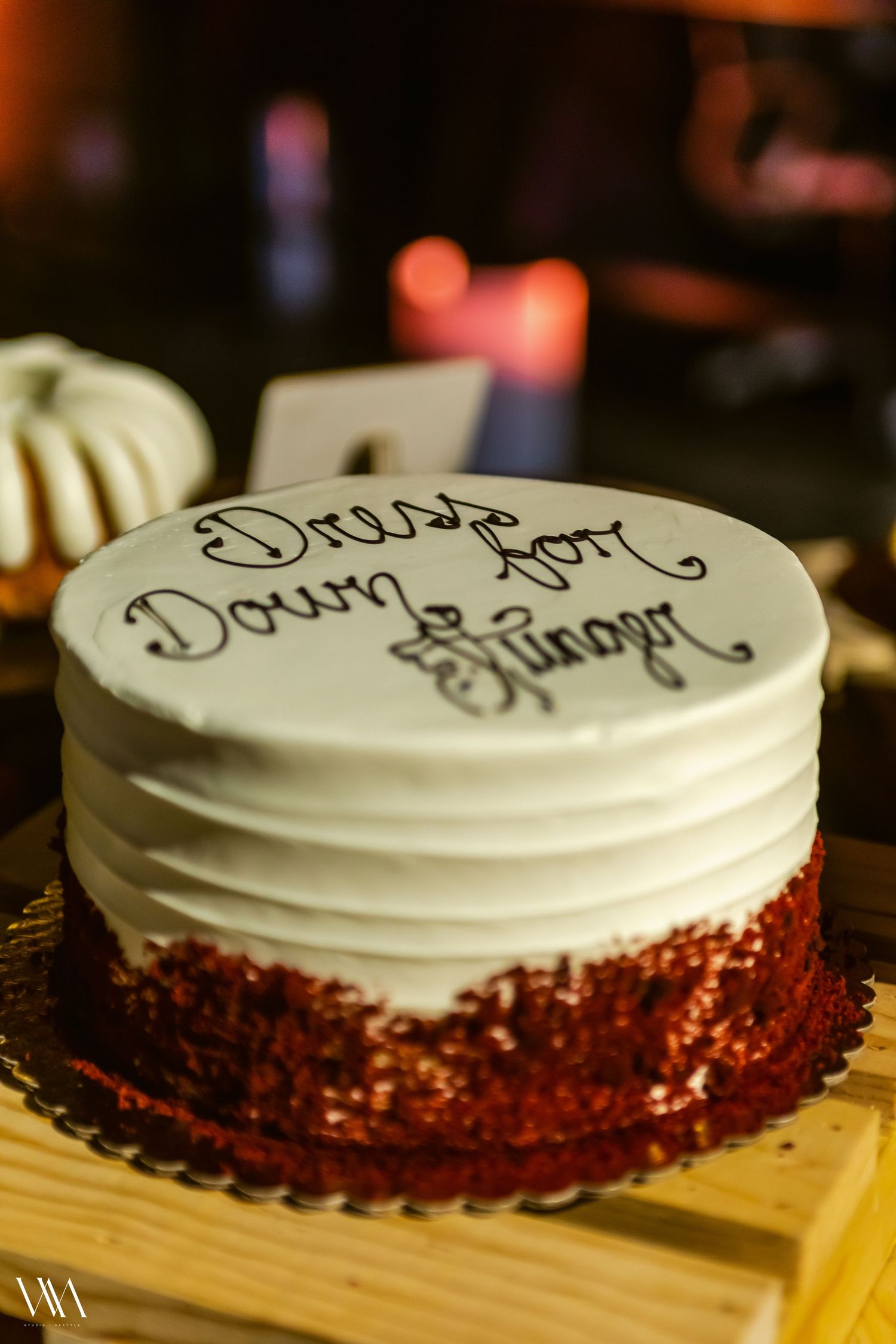 Red velvet cake with white frosting inscribed with dress code down ginger in black cursive lettering on wooden board.