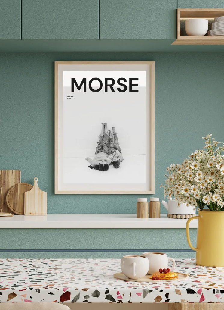 Framed MORSE poster with black and white photo art hanging in a modern kitchen with green walls and terrazzo countertop.
