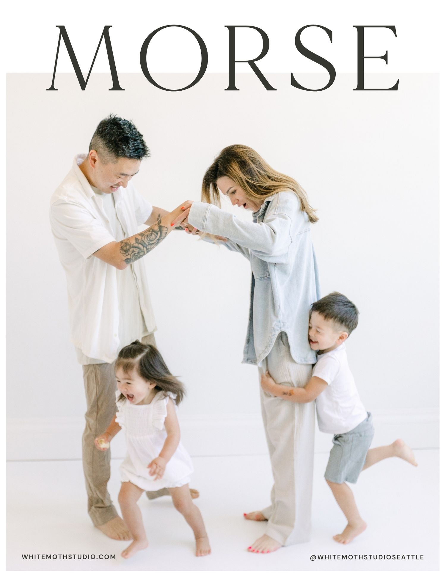 A joyful family of four poses playfully in a white studio, with parents and two young children laughing and dancing together.