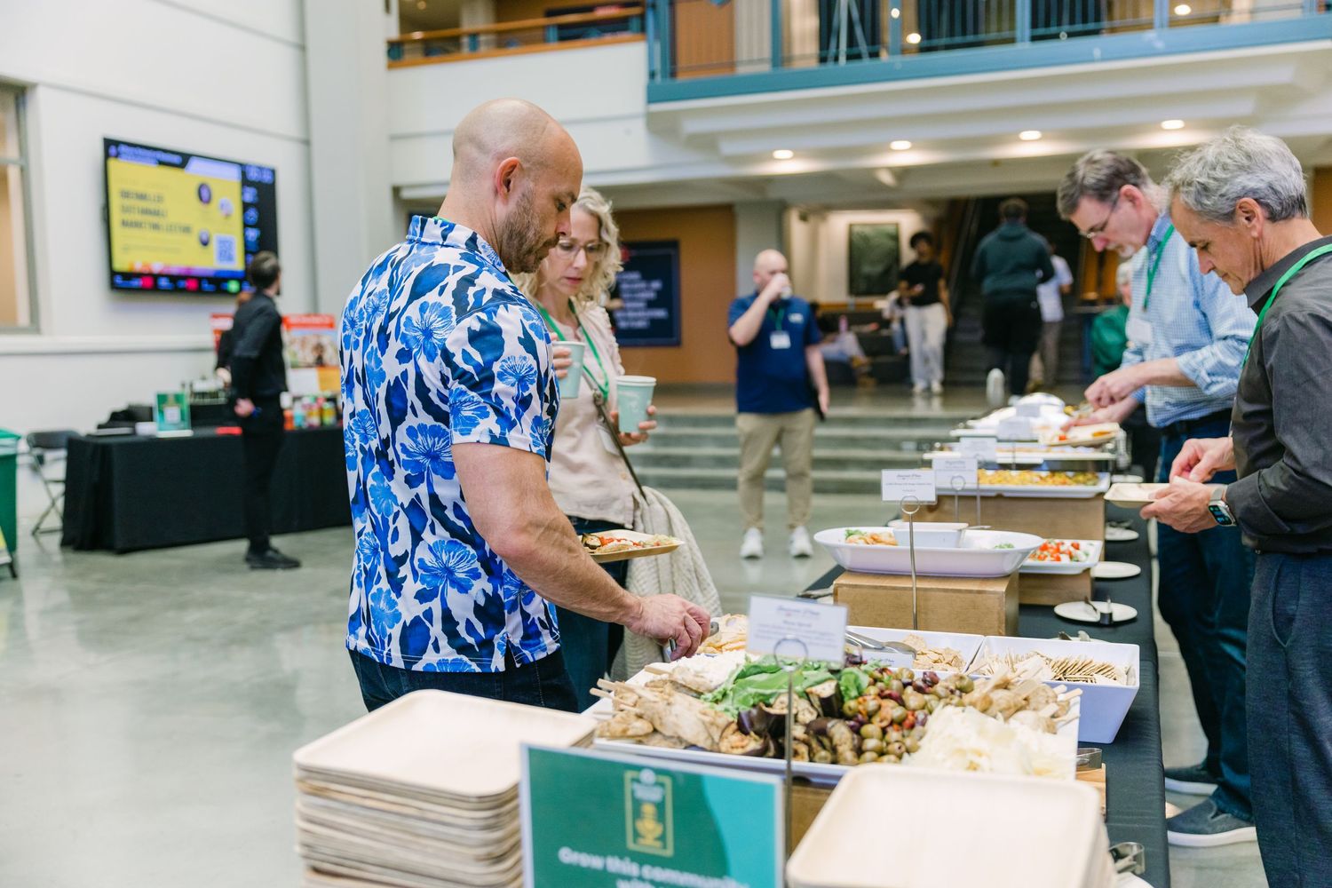 People serving themselves at a buffet table during a catered corporate event in a modern venue.