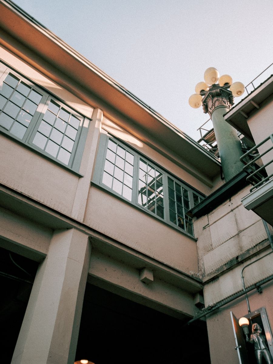 Low-angle view of a historic building exterior with grid windows and ornate street lamp at dusk.