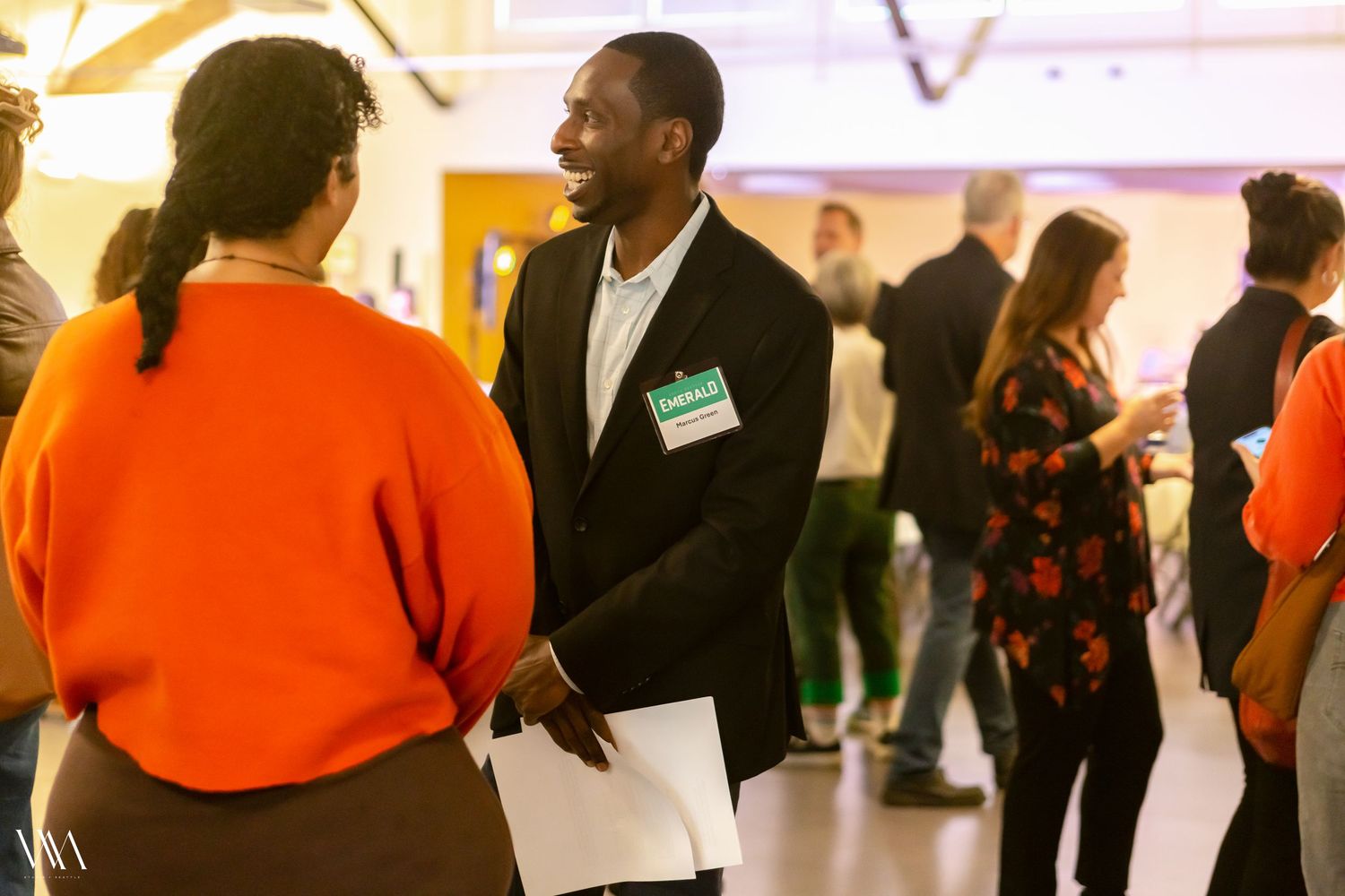 Professional networking event with diverse attendees engaged in conversation in a bright modern venue.