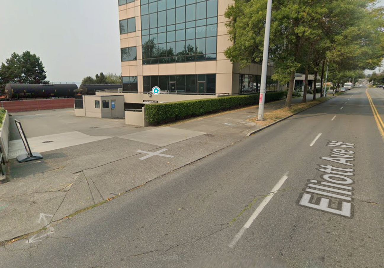 Street view of Elliott Avenue with a modern office building, parking area, and tree-lined sidewalk in an urban setting.
