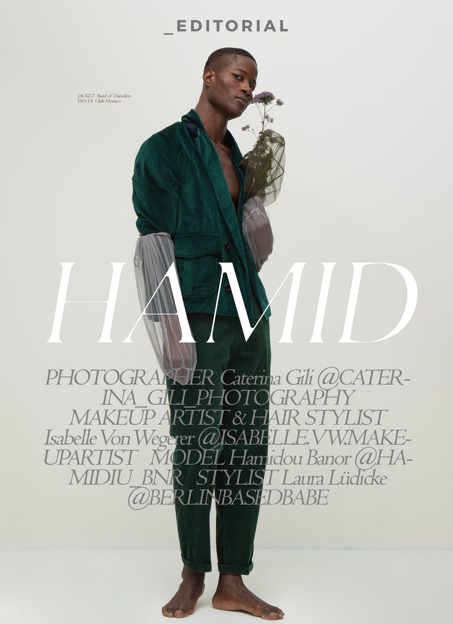 Editorial fashion feature of model Hamidou Banor in green velvet outfit holding dried flowers against white background.