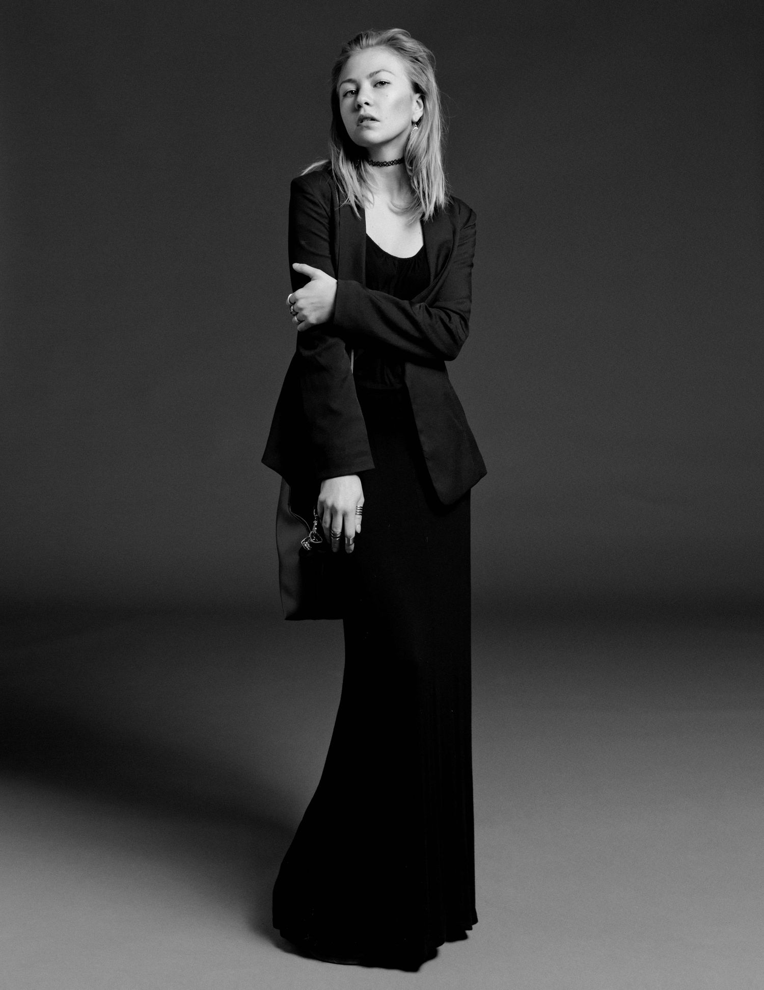 Black and white full-length portrait of a woman in elegant black blazer and maxi skirt.