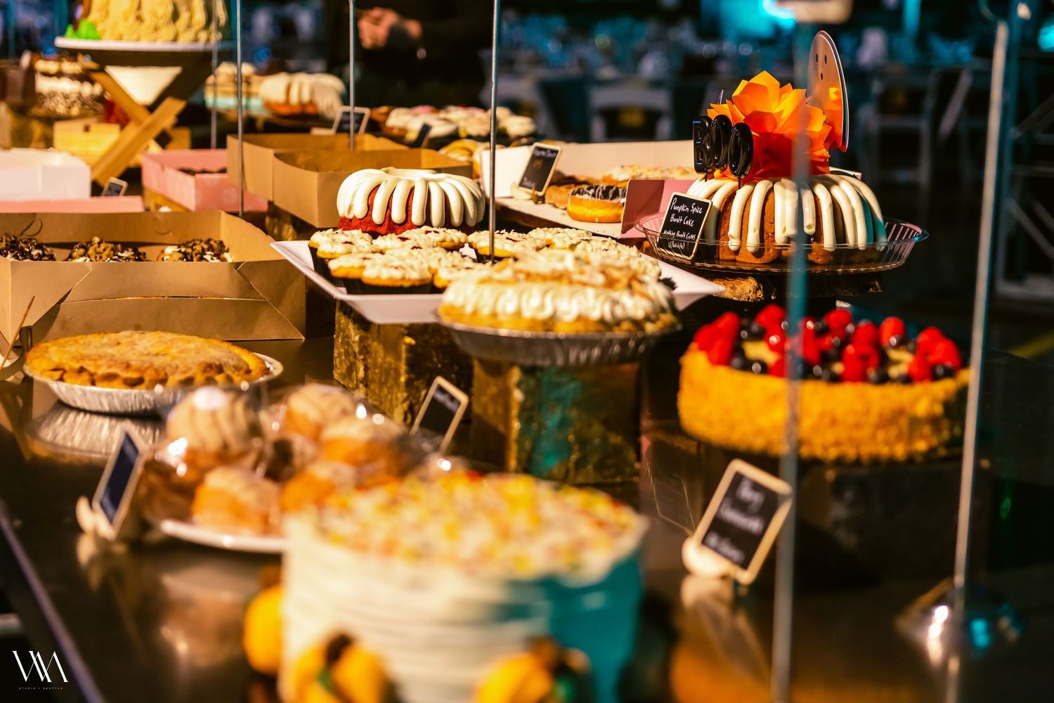 Colorful dessert display featuring bundt cakes, pies, and decorated cakes at a catering buffet.