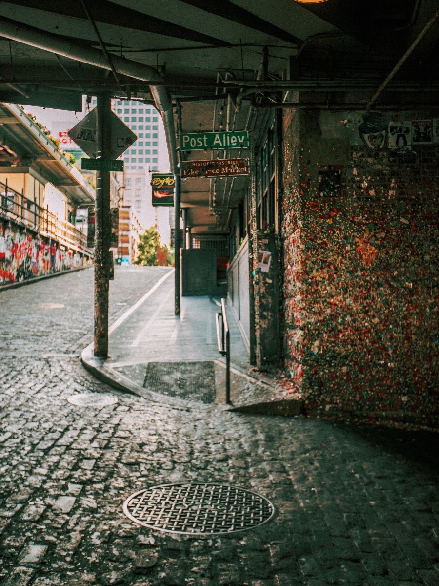 Post Alley in Seattle featuring iconic gum wall covered in colorful chewing gum on cobblestone street.