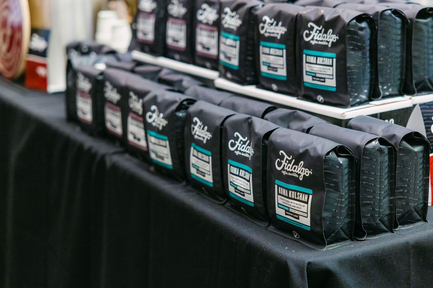Rows of Fidelity Coffee bags displayed on a black tablecloth at a coffee tasting event.
