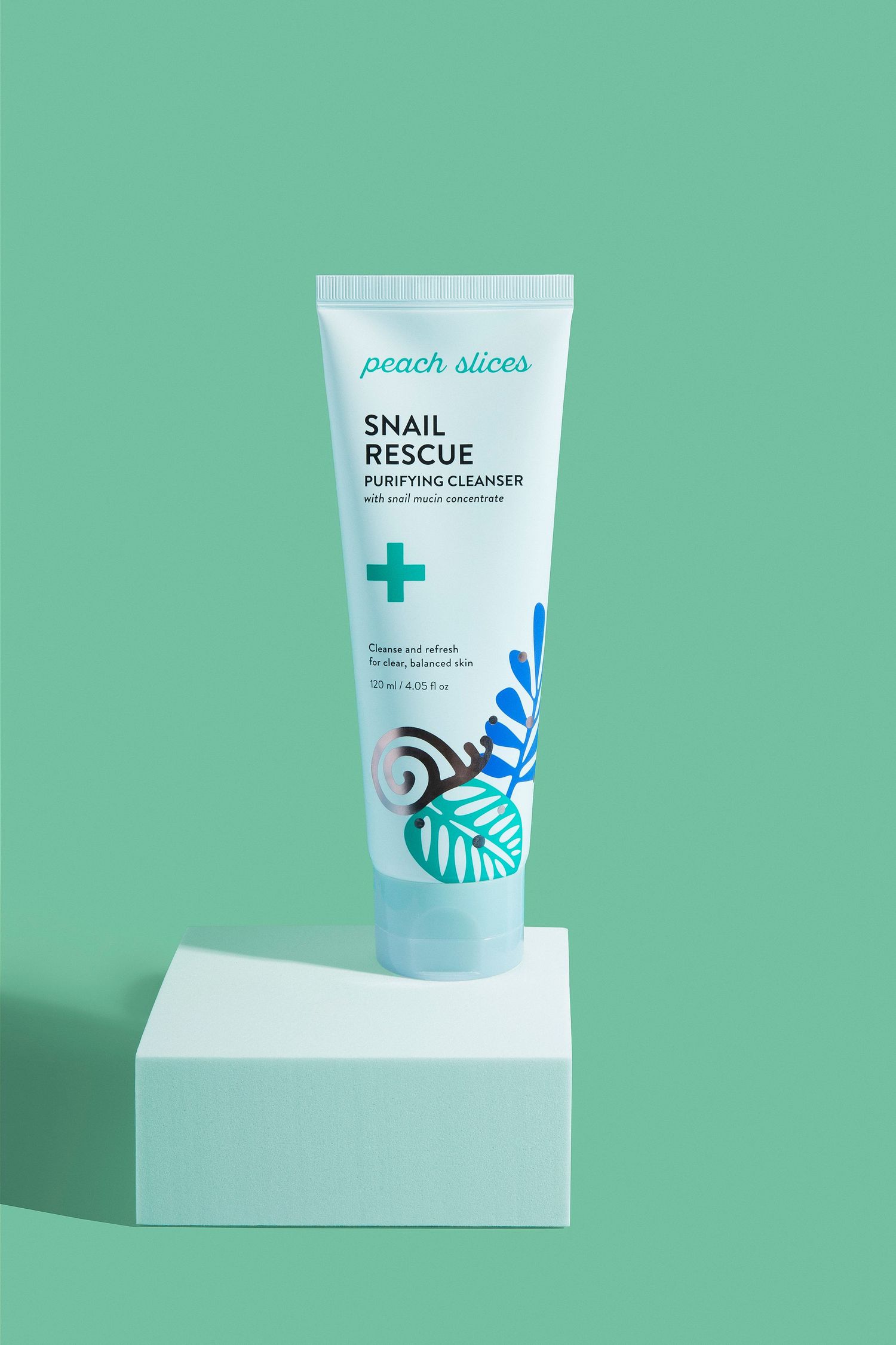 Peach Slices Snail Rescue Purifying Cleanser tube with snail mucin on a white pedestal against mint background.