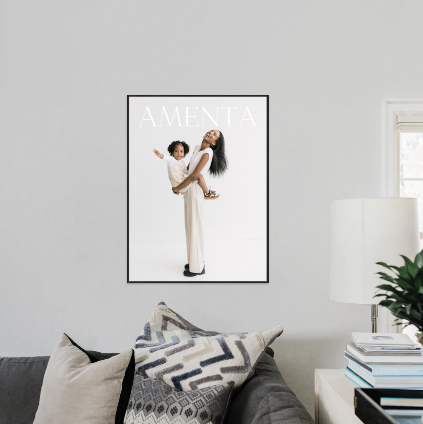 Framed AMENEX magazine cover poster featuring two people, displayed above a modern gray sofa in a minimalist living room.
