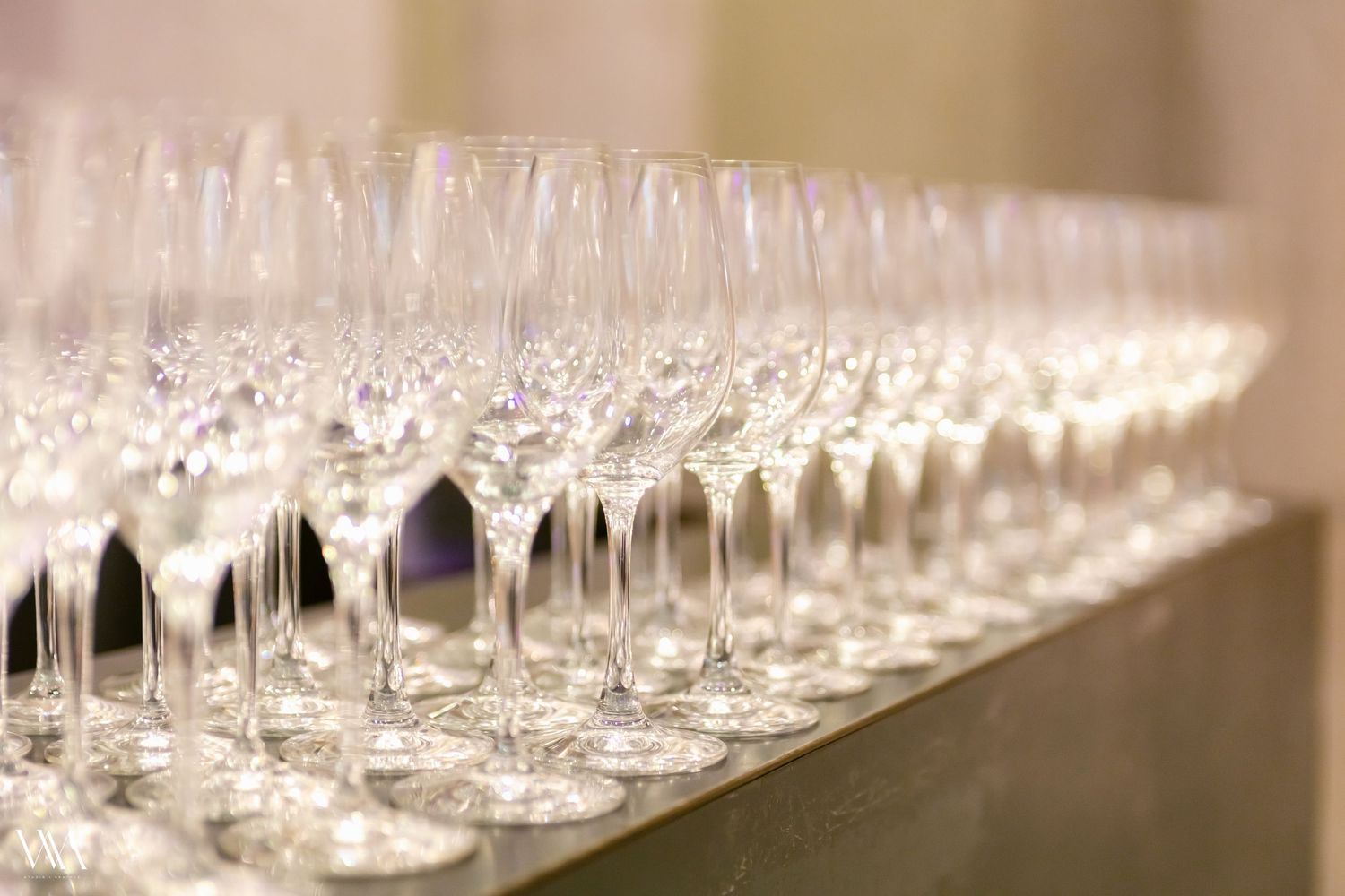 Rows of elegant empty crystal champagne flutes lined up on a table for a formal event or celebration.