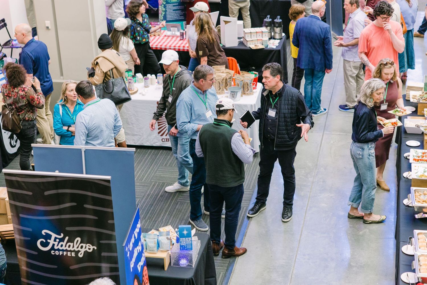 Overhead view of a busy trade show floor with vendors and attendees at Fidalgo coffee exhibition.