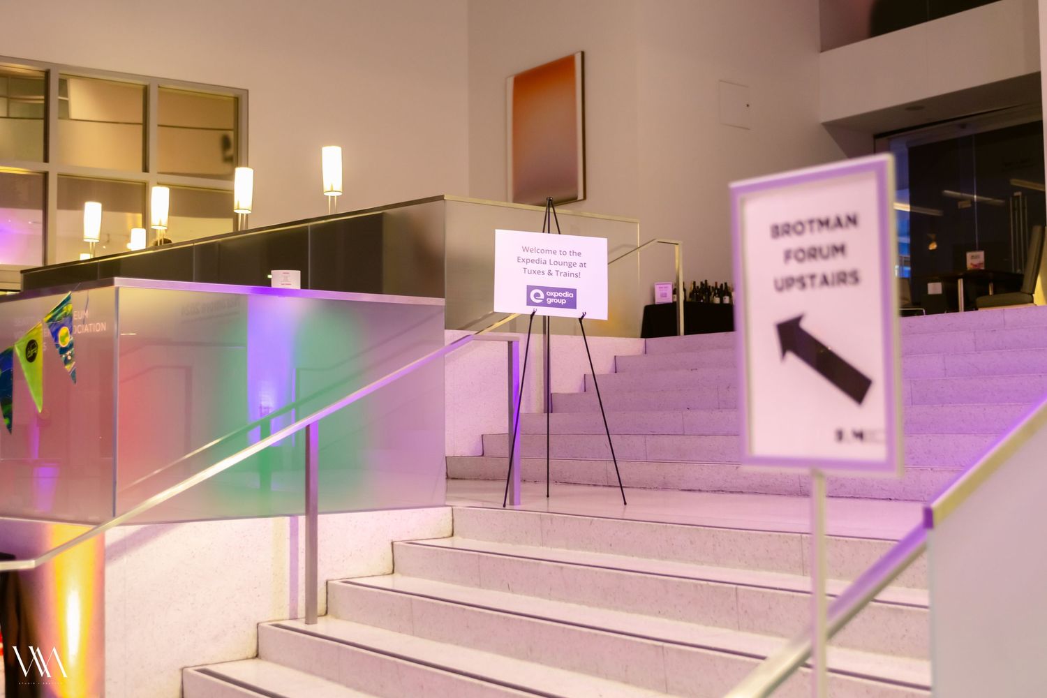 Brotman Forum upstairs entrance with illuminated steps and directional signs at a modern event venue.
