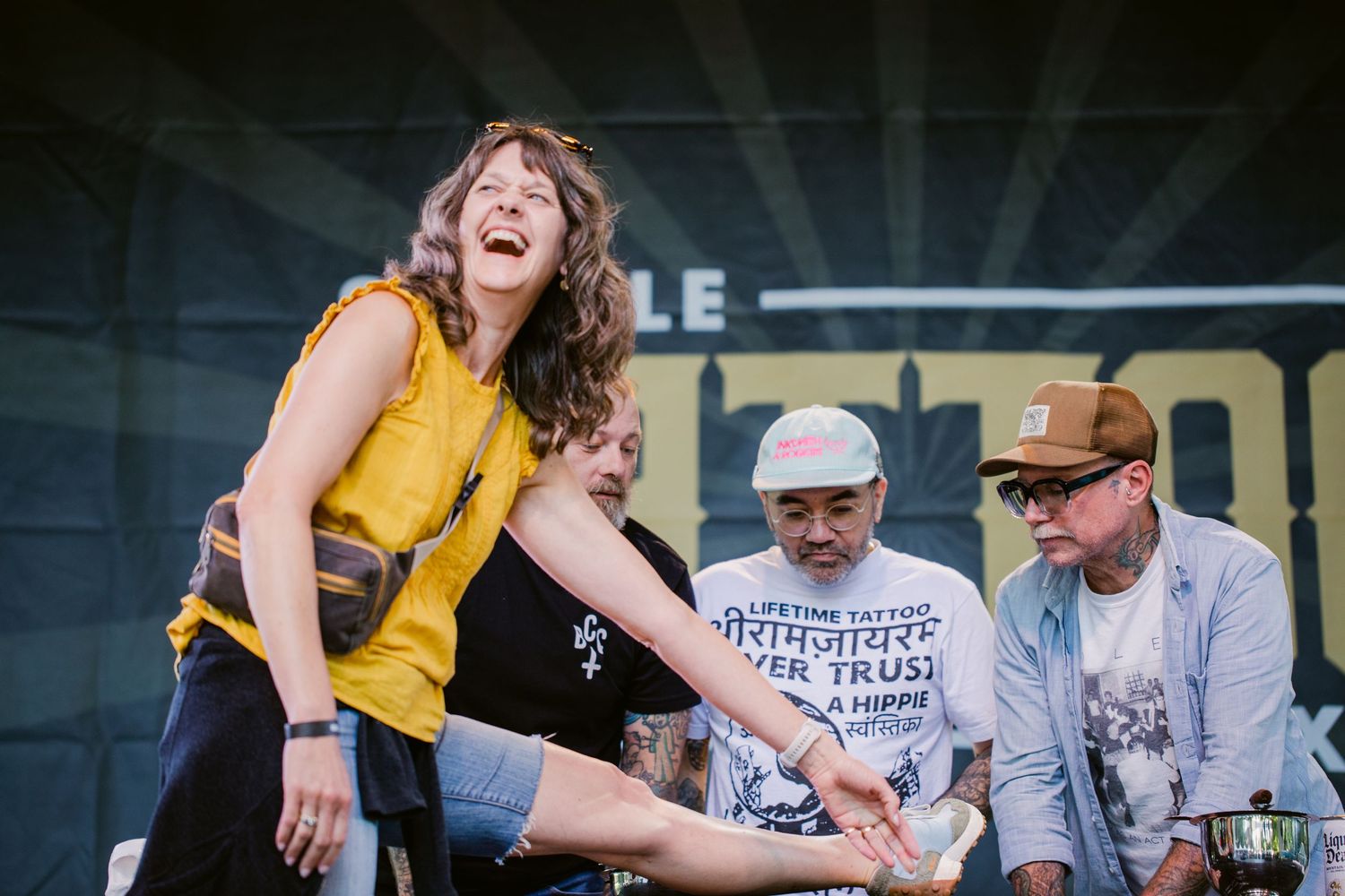 Energetic female performer dancing on stage at a live outdoor Tattoo festival event.