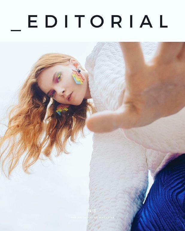 Editorial magazine cover with model in white coat reaching toward camera with colorful earrings.