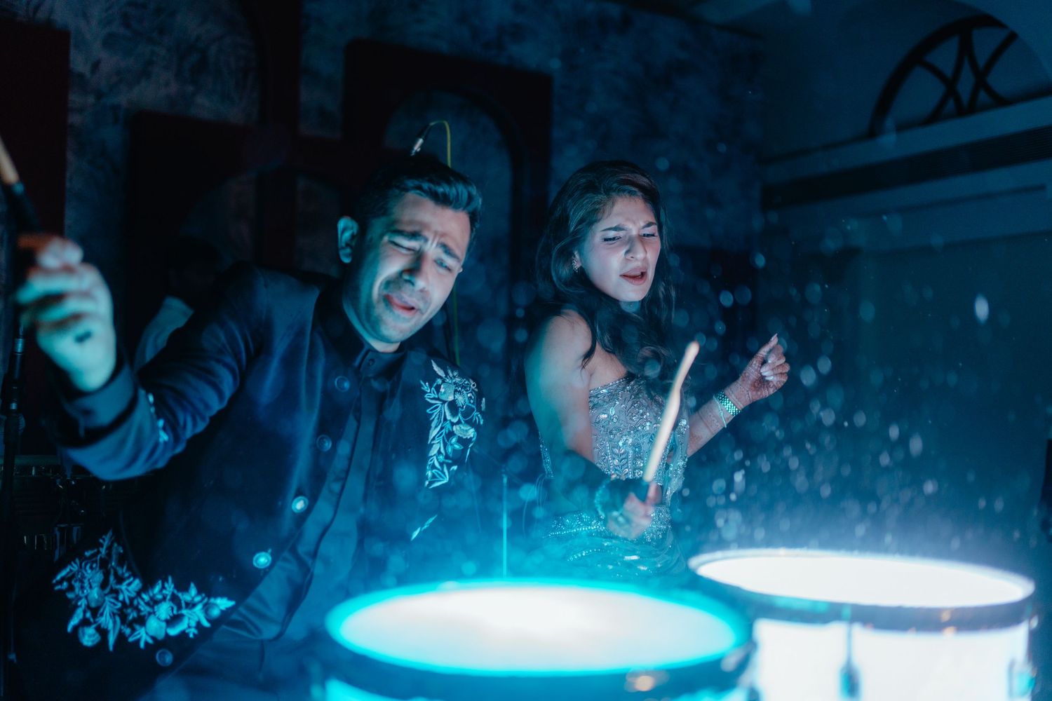 A dramatic scene with blue lighting shows several figures in dark silhouettes against a glowing background.