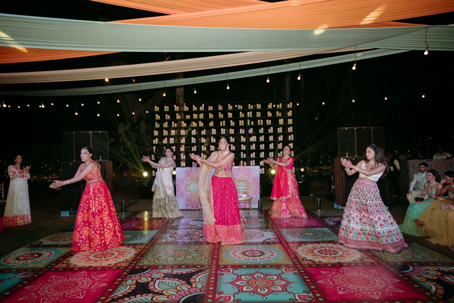 A fashion show runway displays a collection of bright pink and floral formal gowns arranged in a gallery setting.
