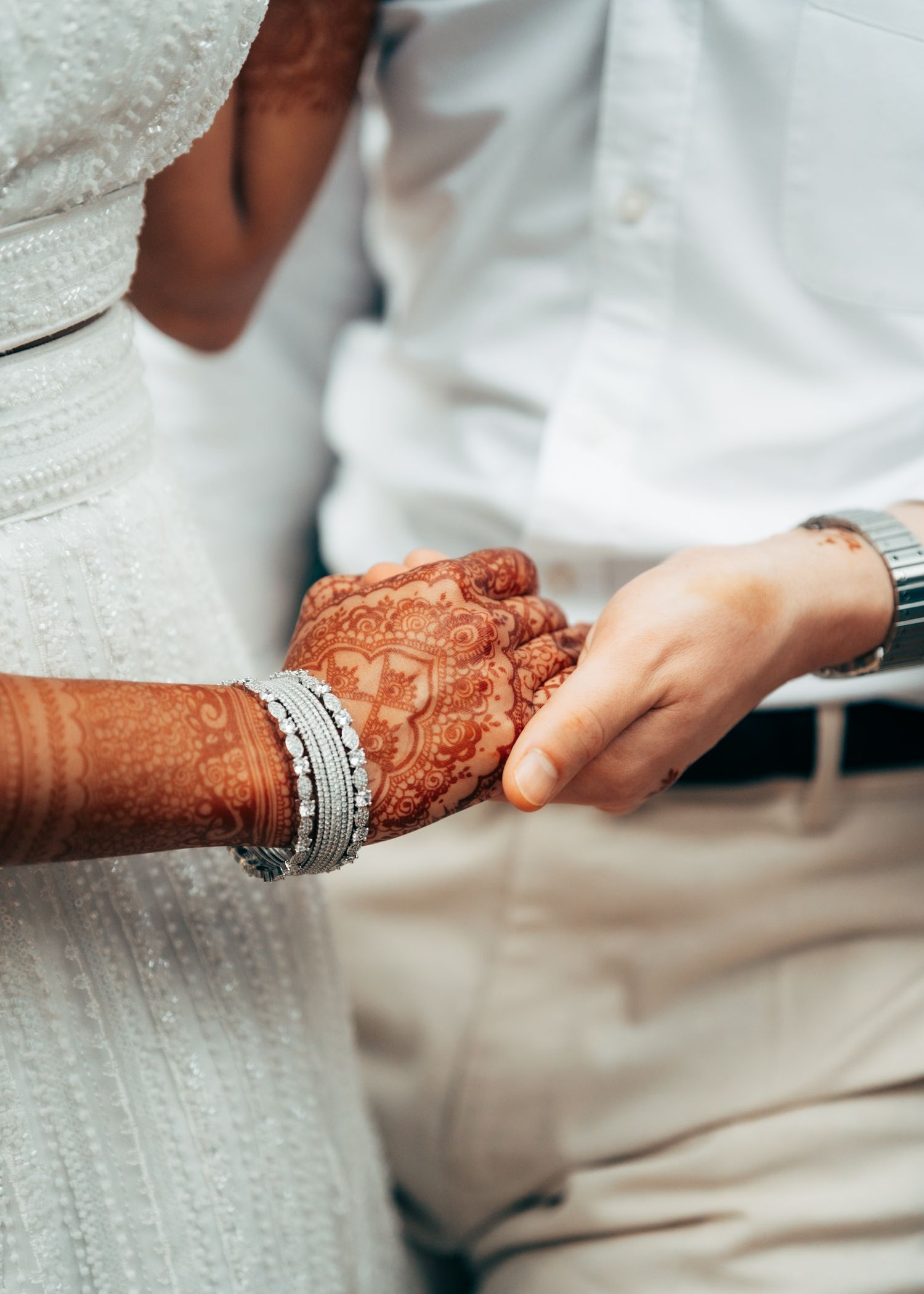 Close-up of hands with traditional mehndi design and silver wedding jewelry.