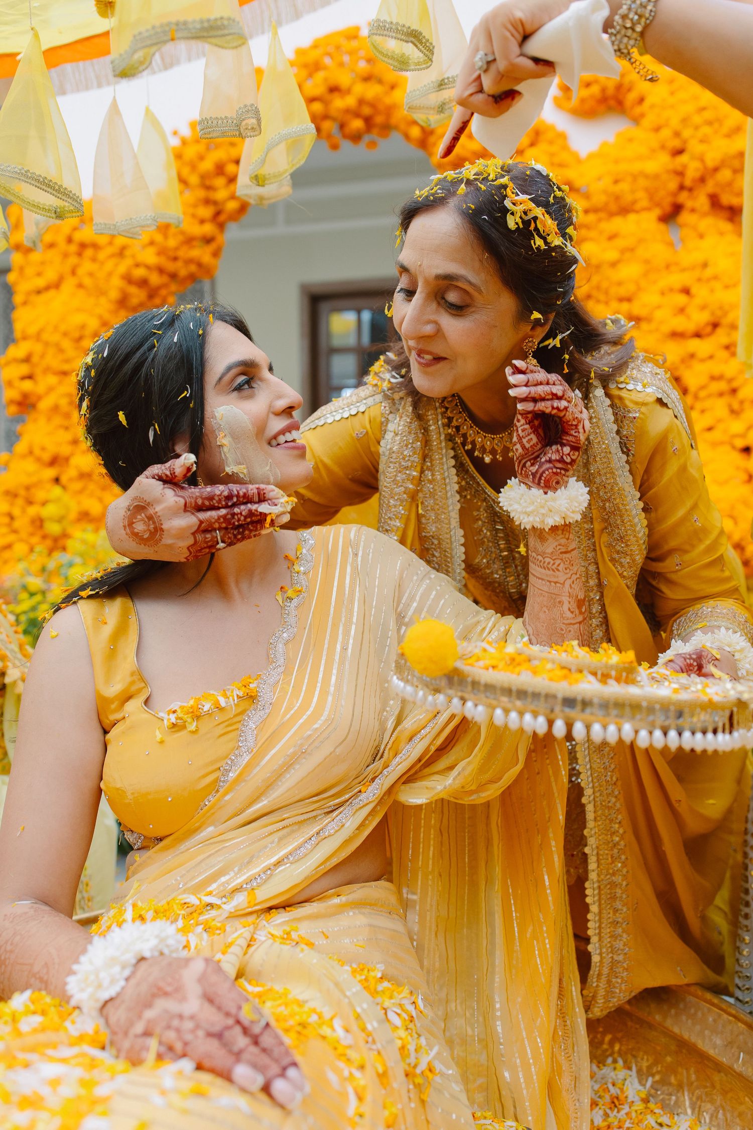 Wedding celebration with yellow outfits and marigold flower decorations in the background.