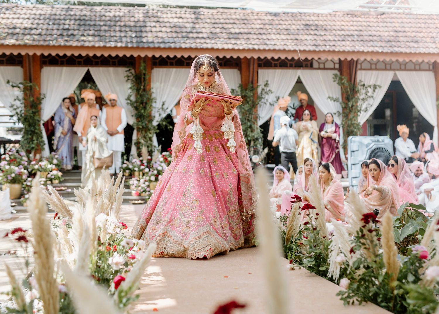 Outdoor wedding venue decorated with pink and white floral arrangements and draping.