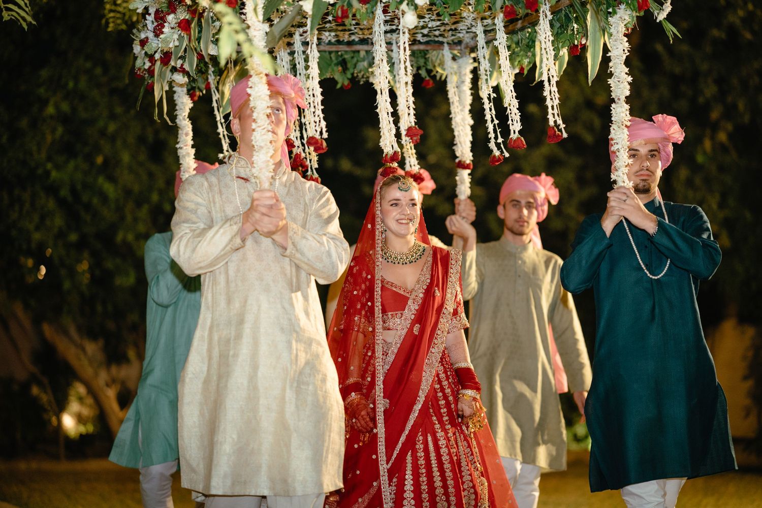 Wedding ceremony setup with hanging floral decorations and guests in traditional attire.