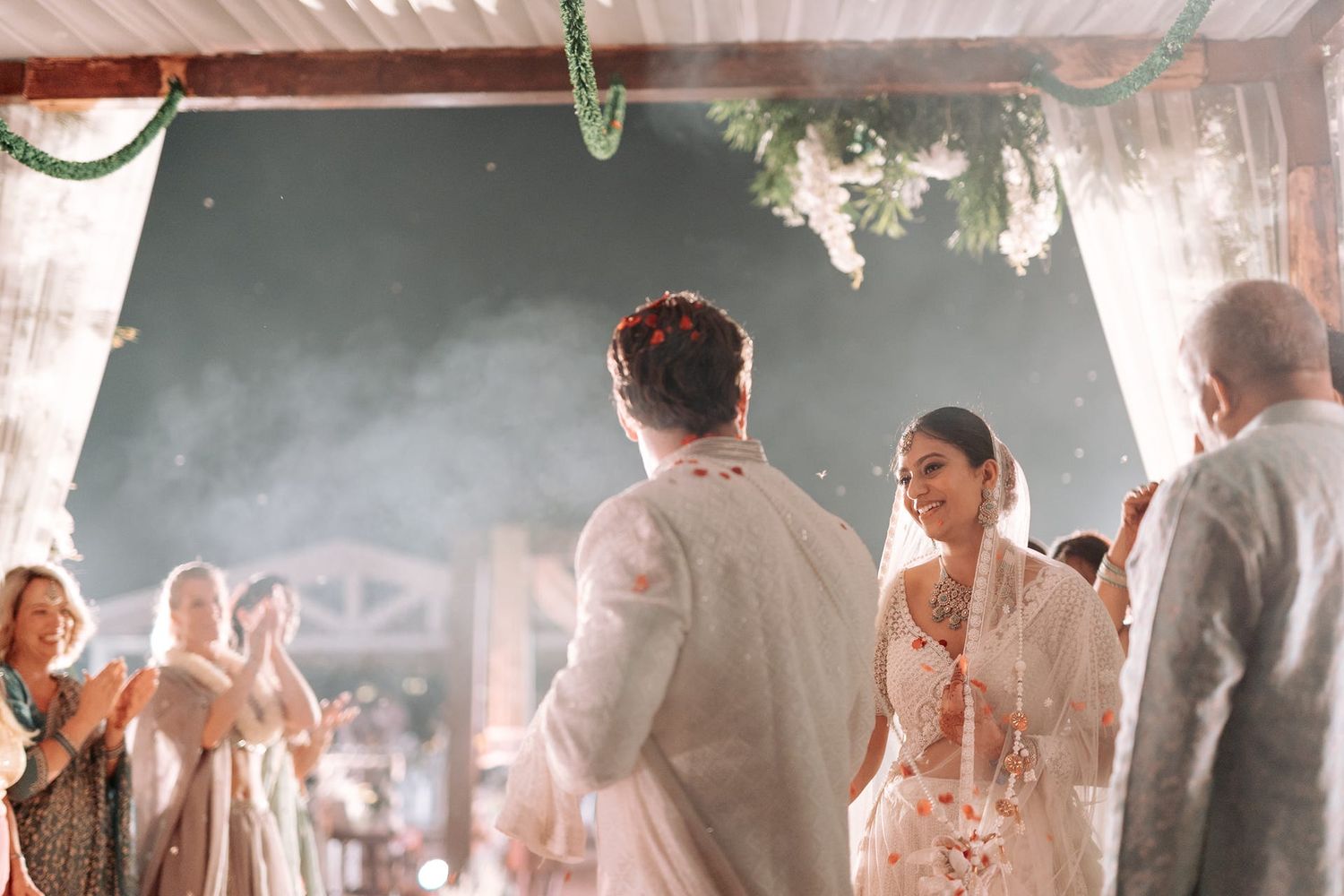 Bride and groom share a romantic moment at an elegant indoor wedding ceremony with floral decor.
