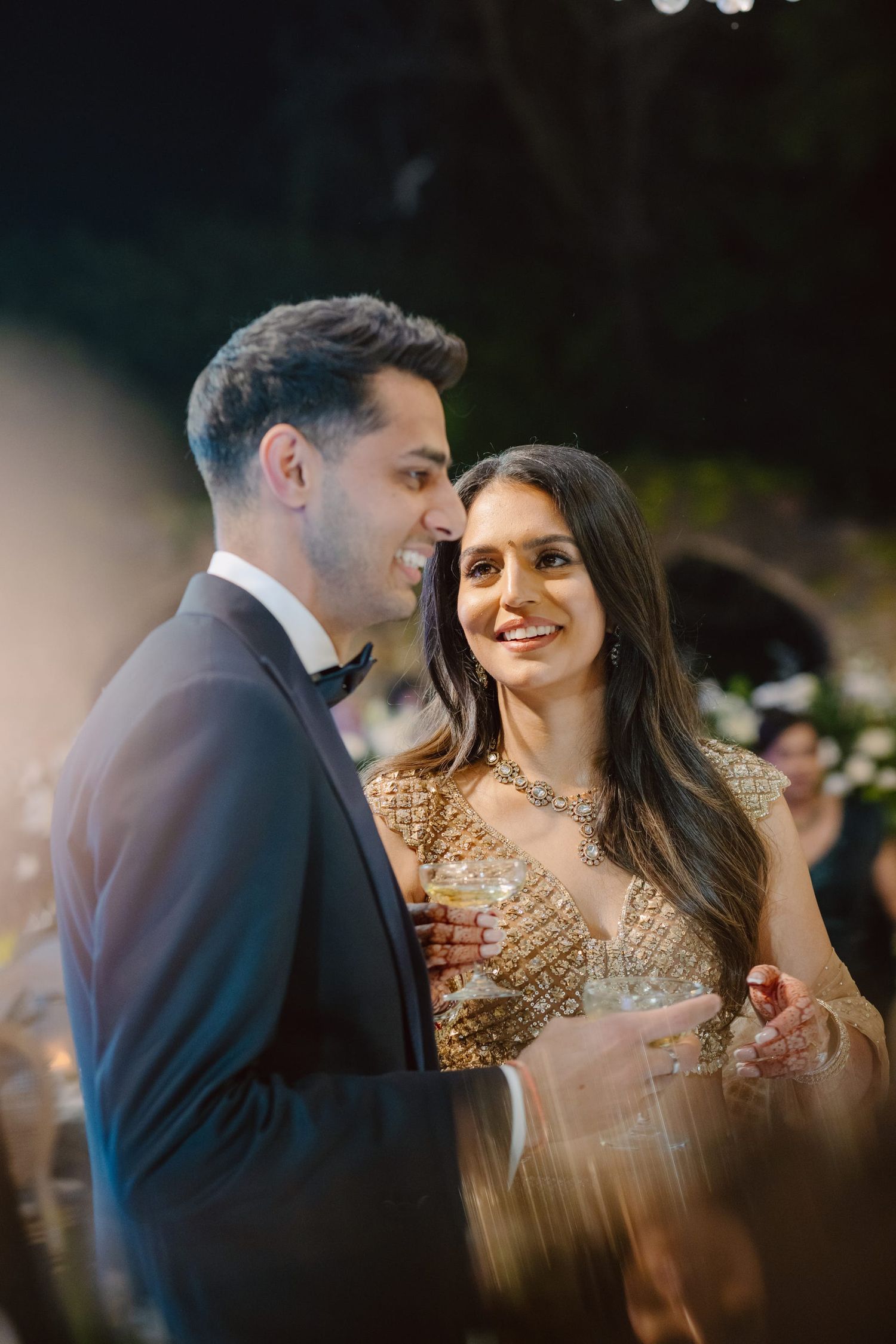 A couple shares an intimate moment at their reception, with the bride wearing a sparkling gold gown.