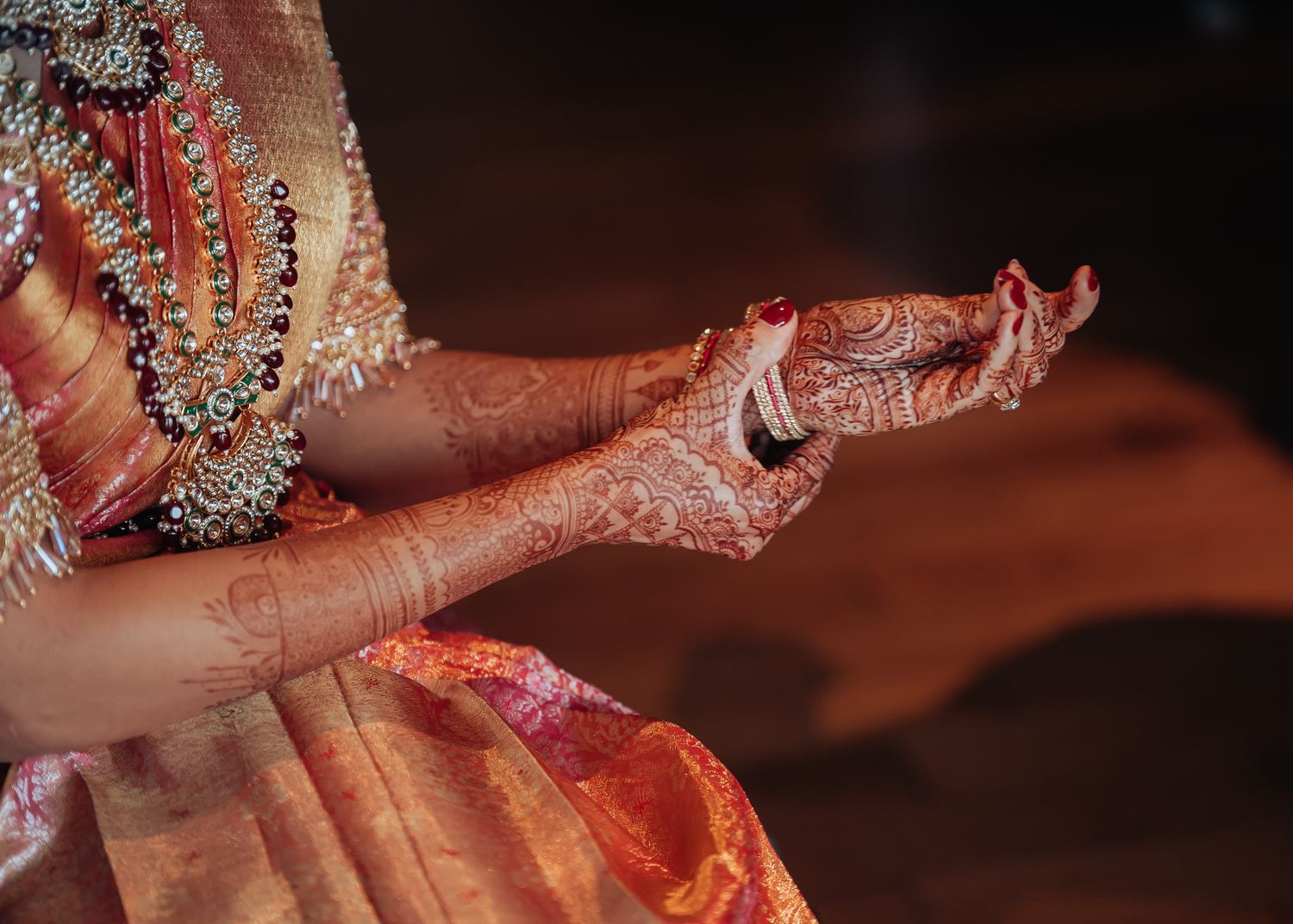 Close-up of traditional bridal jewelry and henna adorned hands.