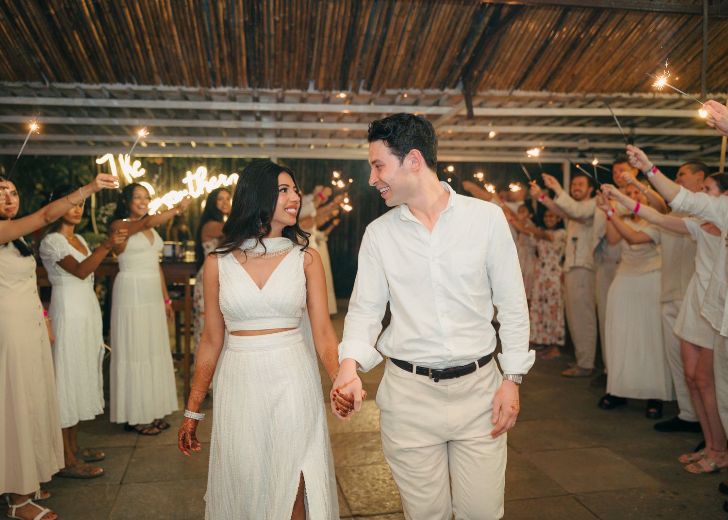 Evening wedding reception with guests dancing in white and cream colored outfits.