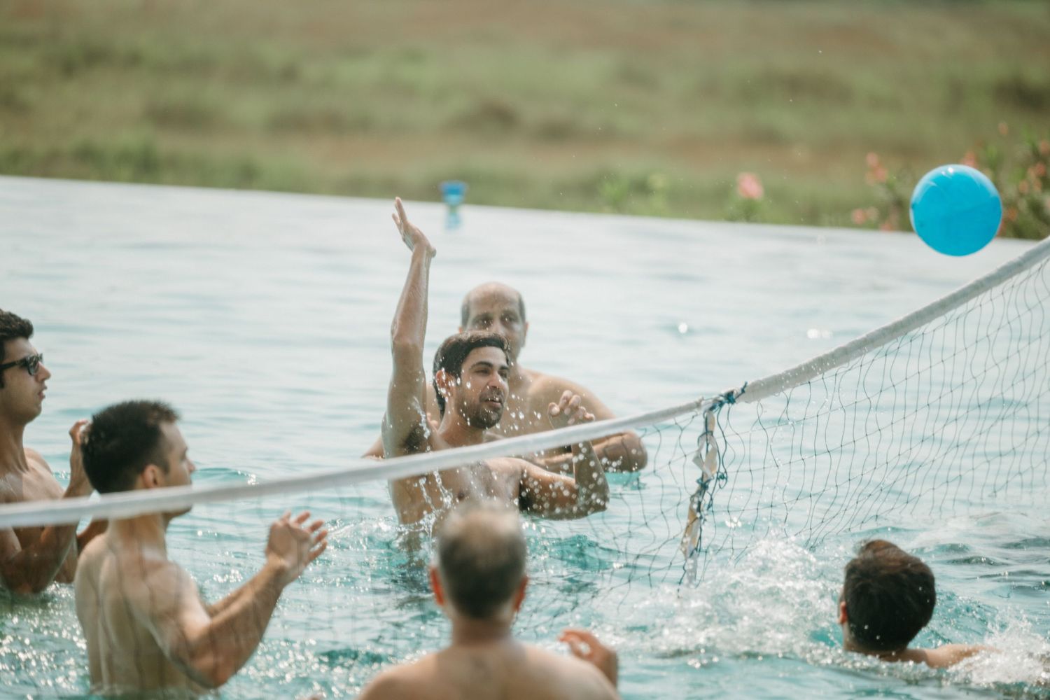 People enjoying a game of volleyball in a swimming pool on a sunny day.