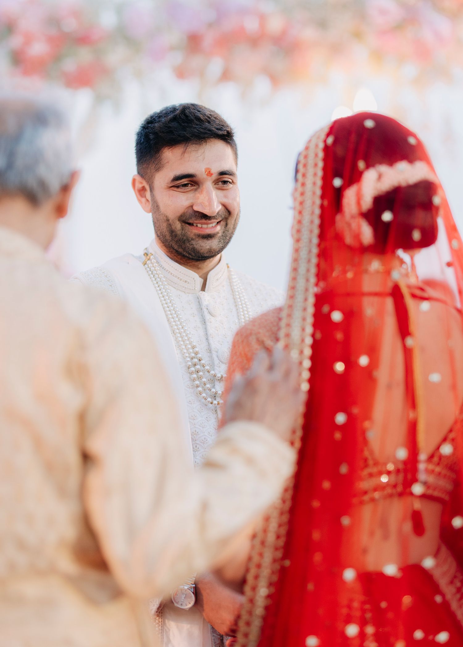 A joyful moment captured during an Indian wedding ceremony with bright red and white traditional attire.