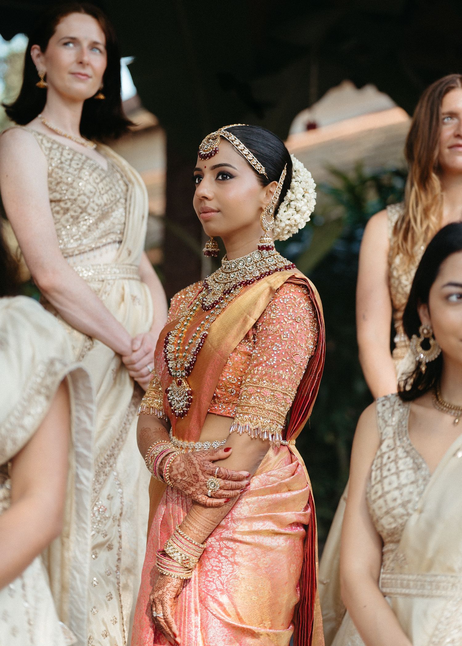Wedding party members in mix of traditional South Asian attire and Western dresses posing together.