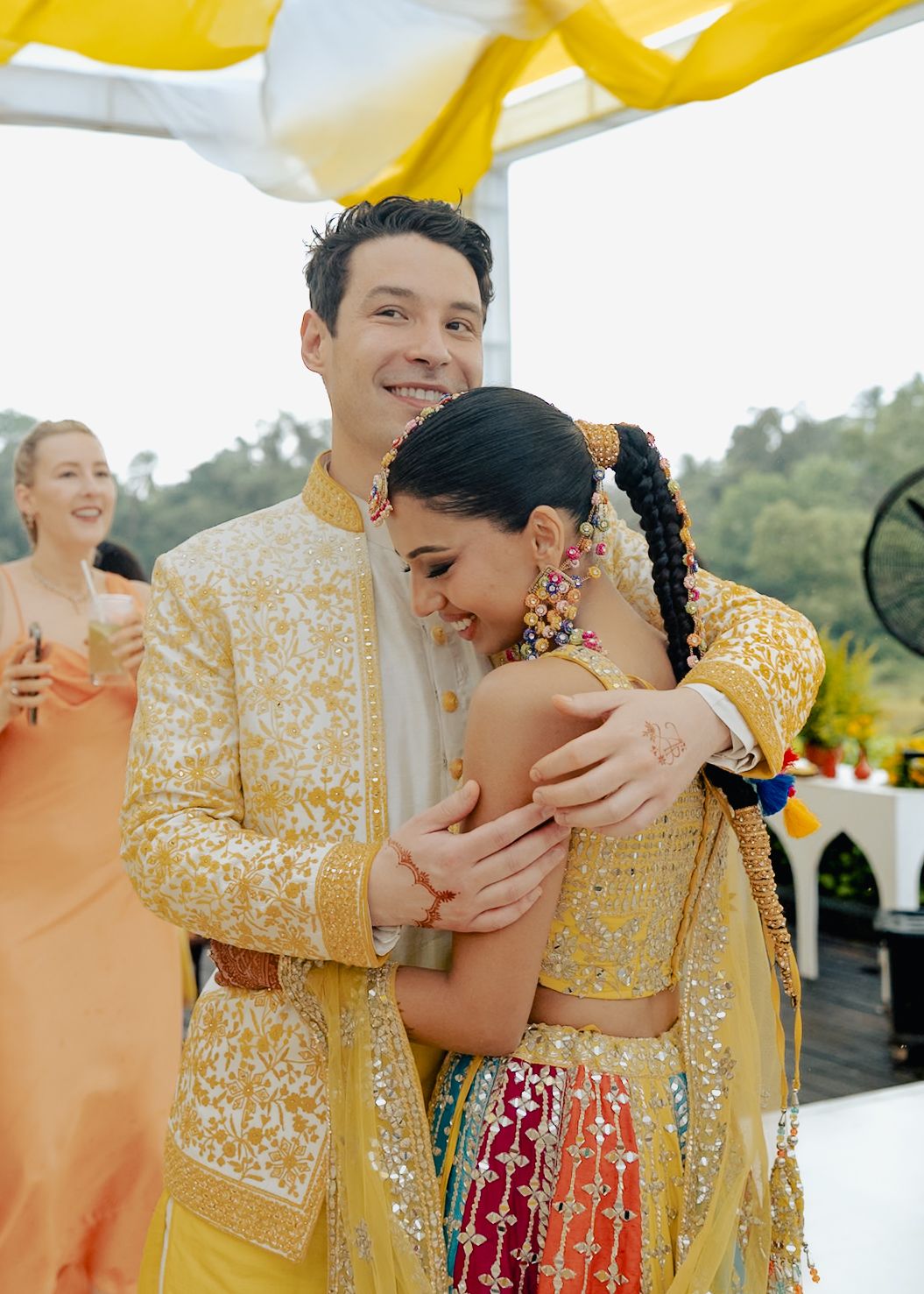 Joyful moments captured at an Indian wedding with the couple in yellow and white traditional attire.