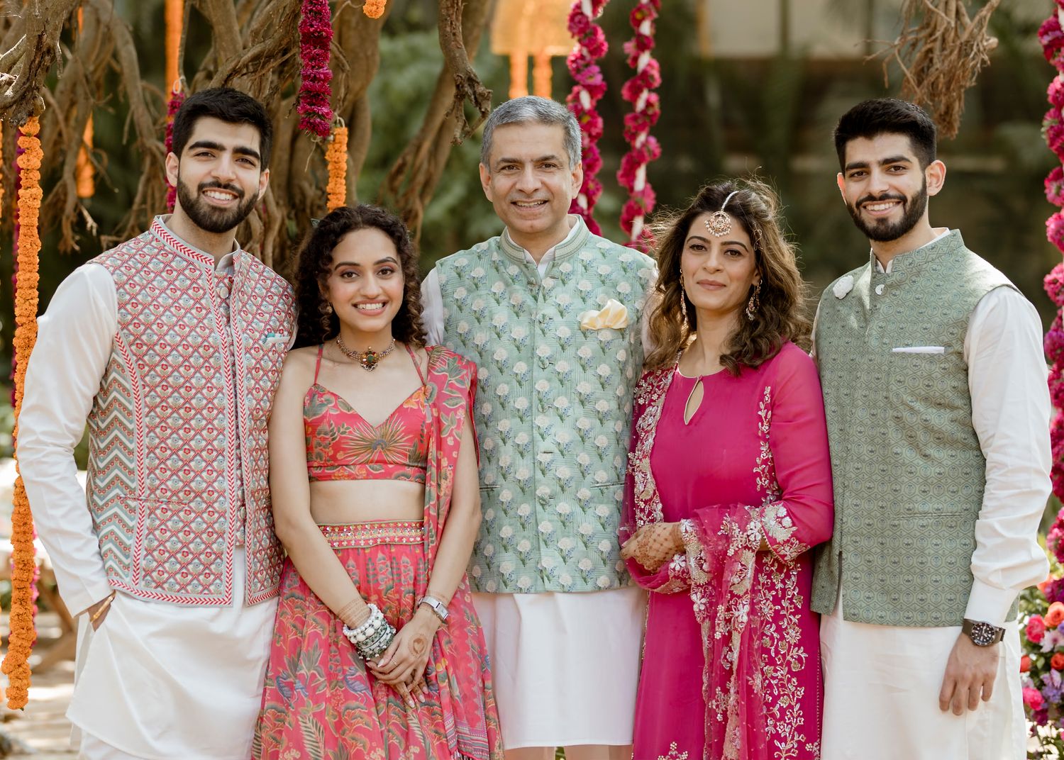Family group photo at Indian celebration wearing coordinated traditional outfits.