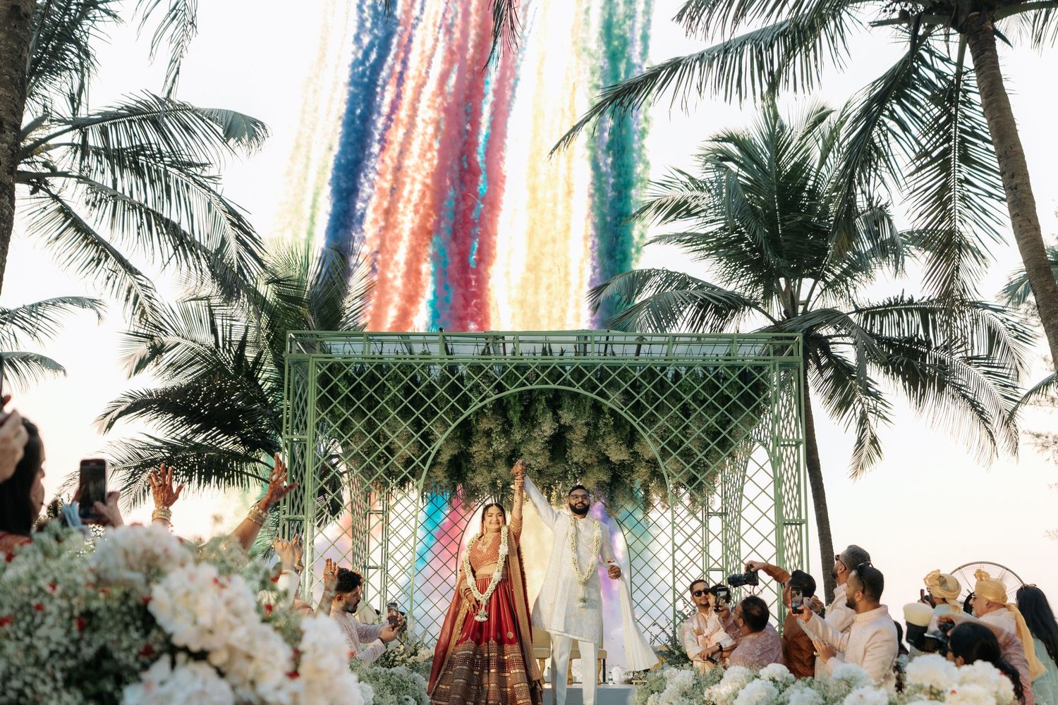 Colorful streamers and decorations hang among palm trees at outdoor wedding venue.