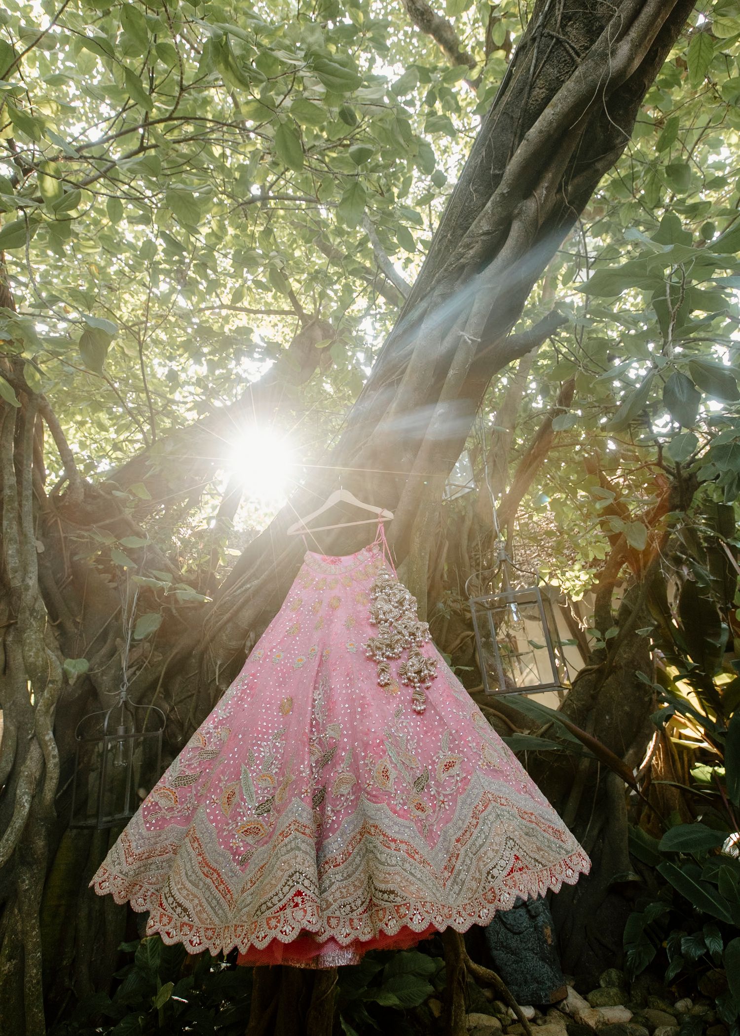 Pink lehenga skirt displayed in natural lighting with trees creating dramatic shadows.