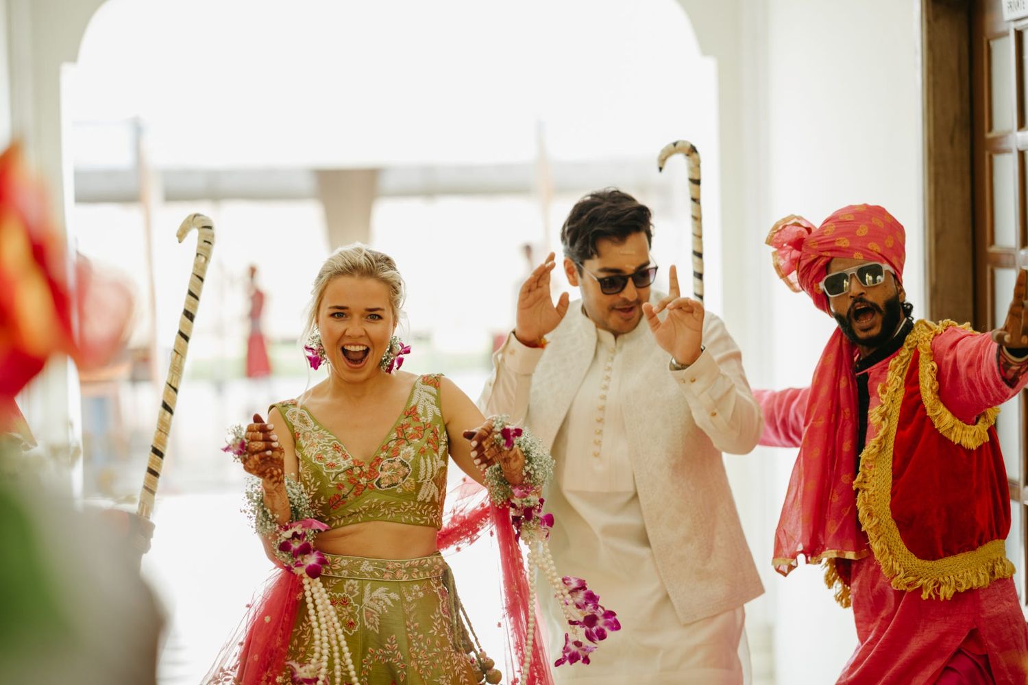 Vibrant wedding celebration with guests in traditional Indian attire throwing colorful flower petals during festivities.