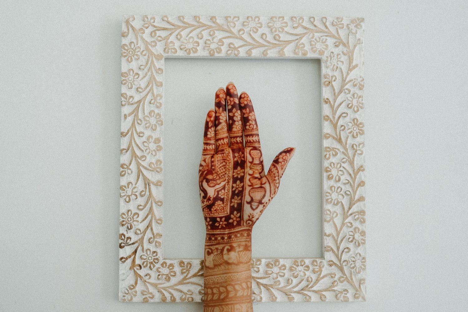 Vintage-style floral frames display delicate henna hand designs in earthy brown tones against a light background.