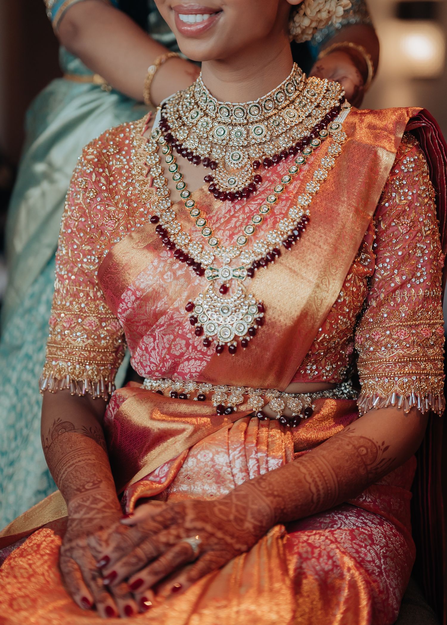 Close-up details of ornate South Asian bridal jewelry and traditional red saree with intricate embellishments.