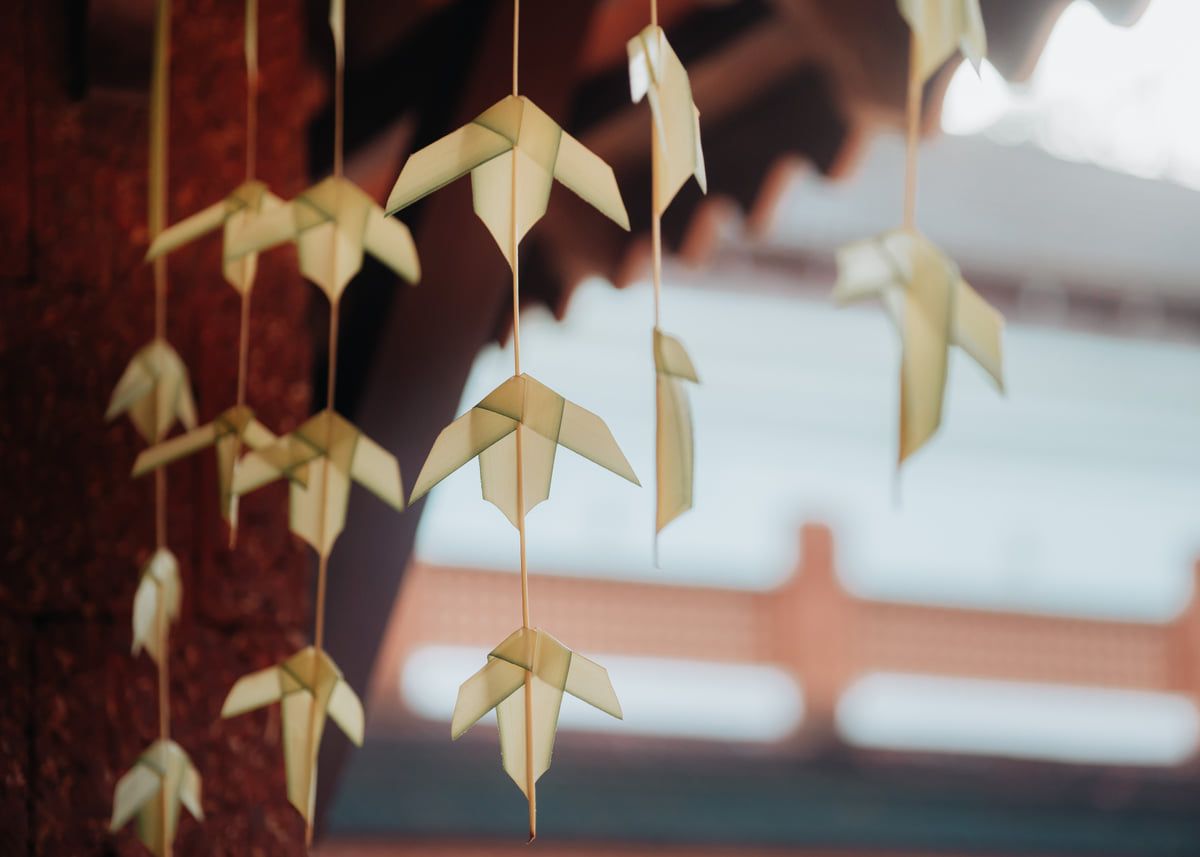 Delicate paper origami flowers hanging from strings in an artistic ceiling display.