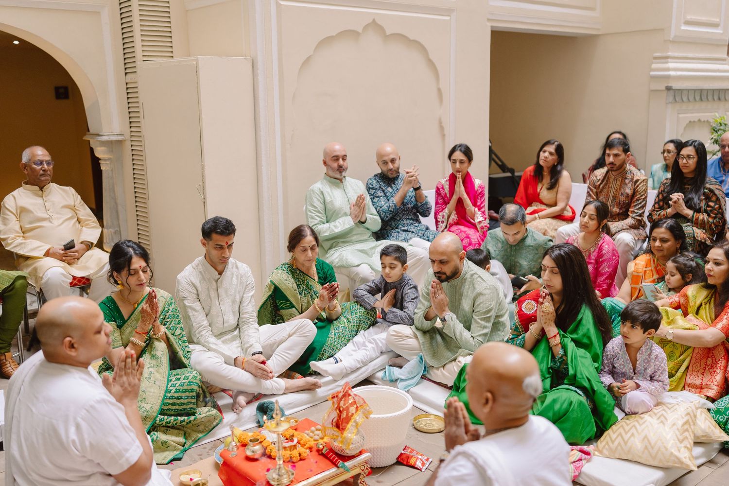 Large group dining together at an elegant Indian wedding reception with white archways.