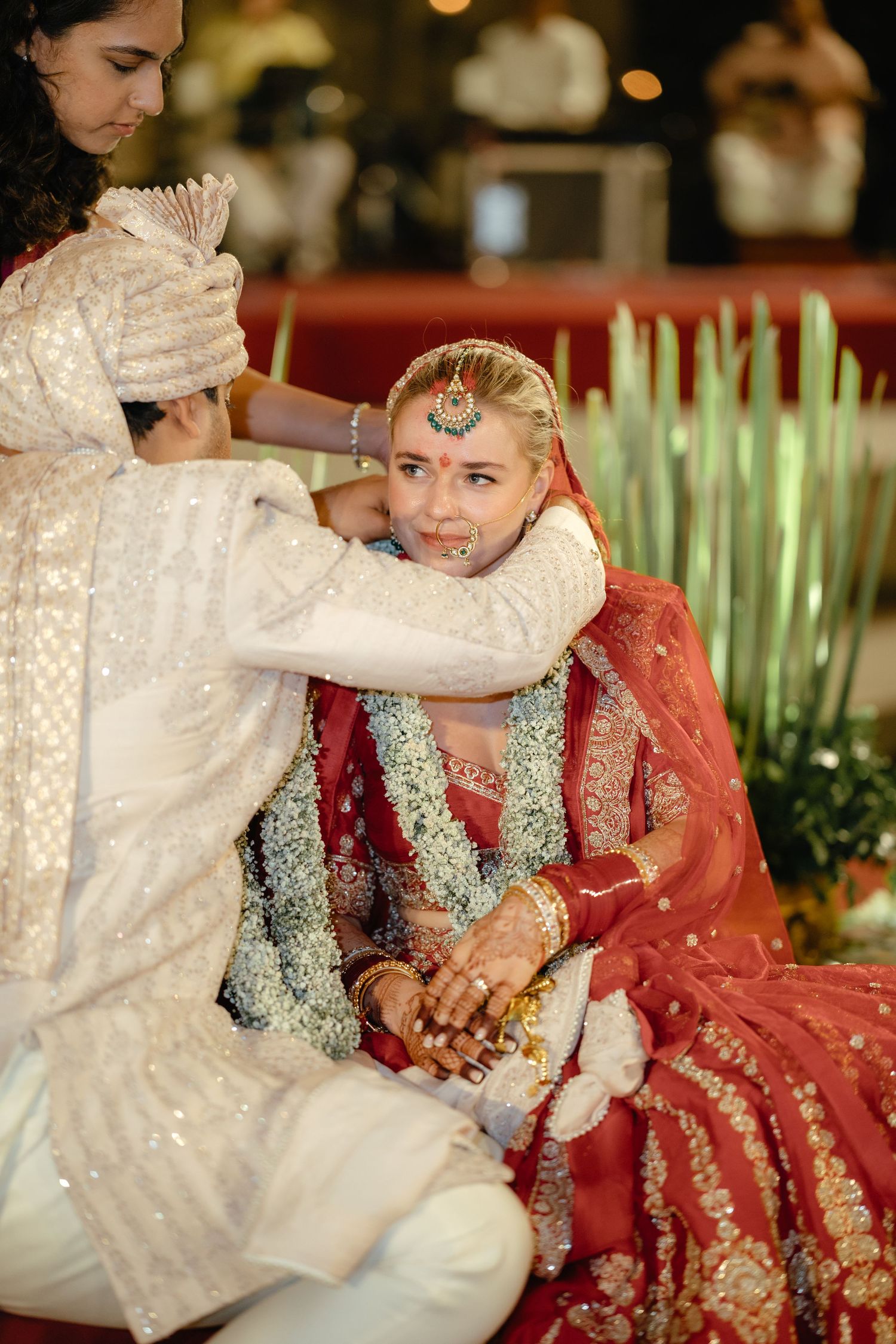 Traditional Indian wedding ceremony showing the bride in red lehenga receiving blessings during a ritual.