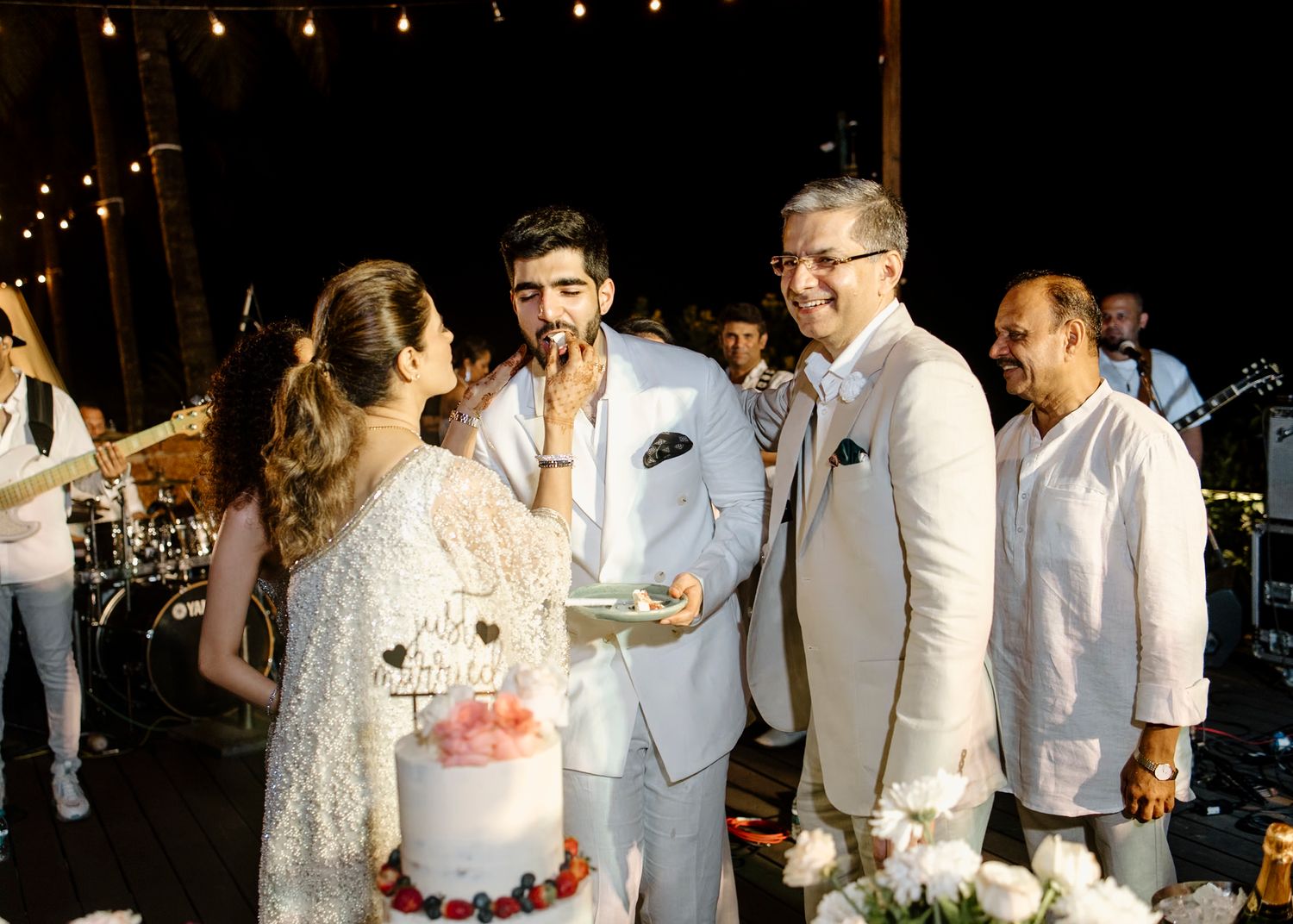 Wedding reception setup with string lights and guests celebrating in the background.