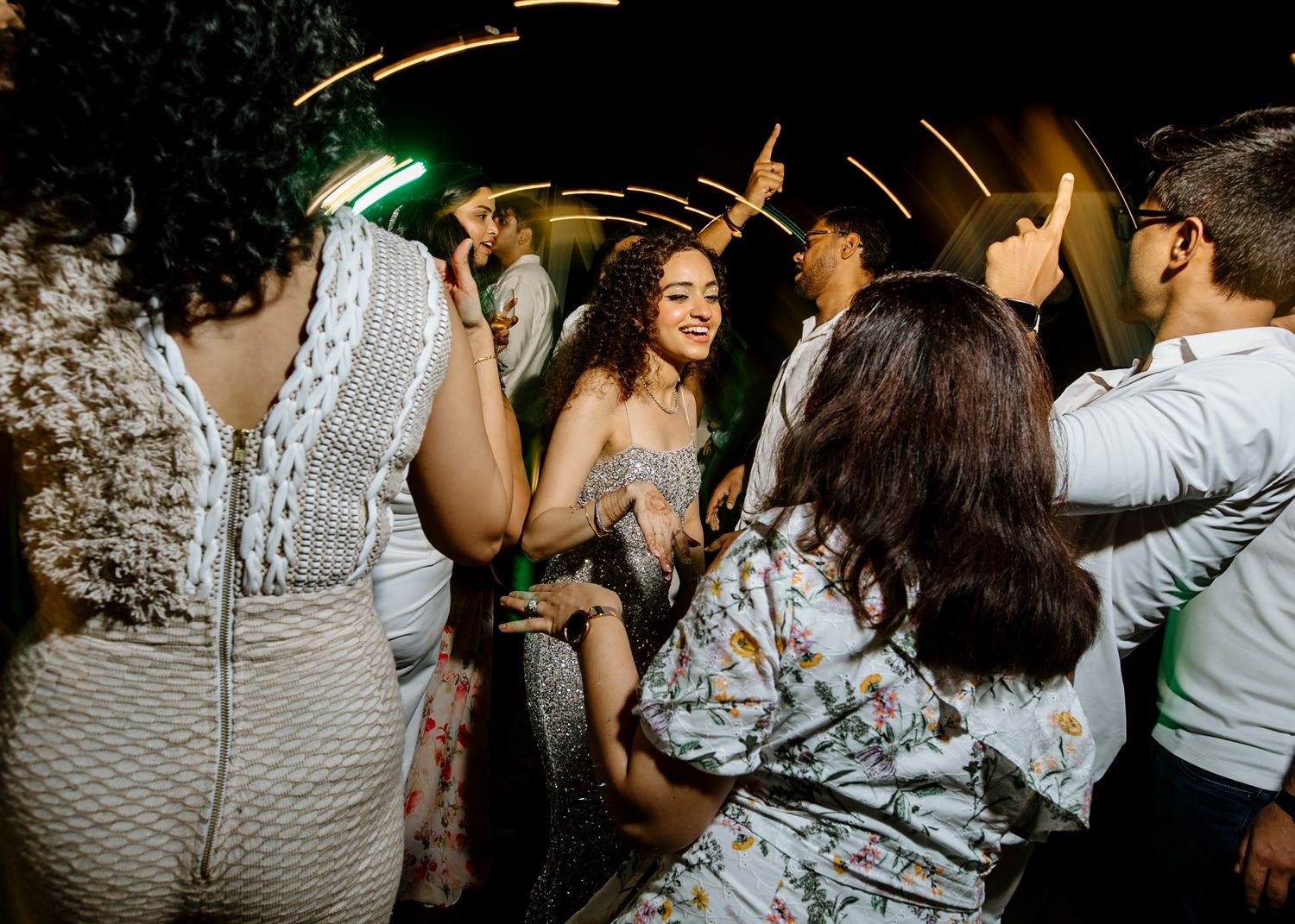 Wedding guests dance and celebrate during a dimly lit evening reception.