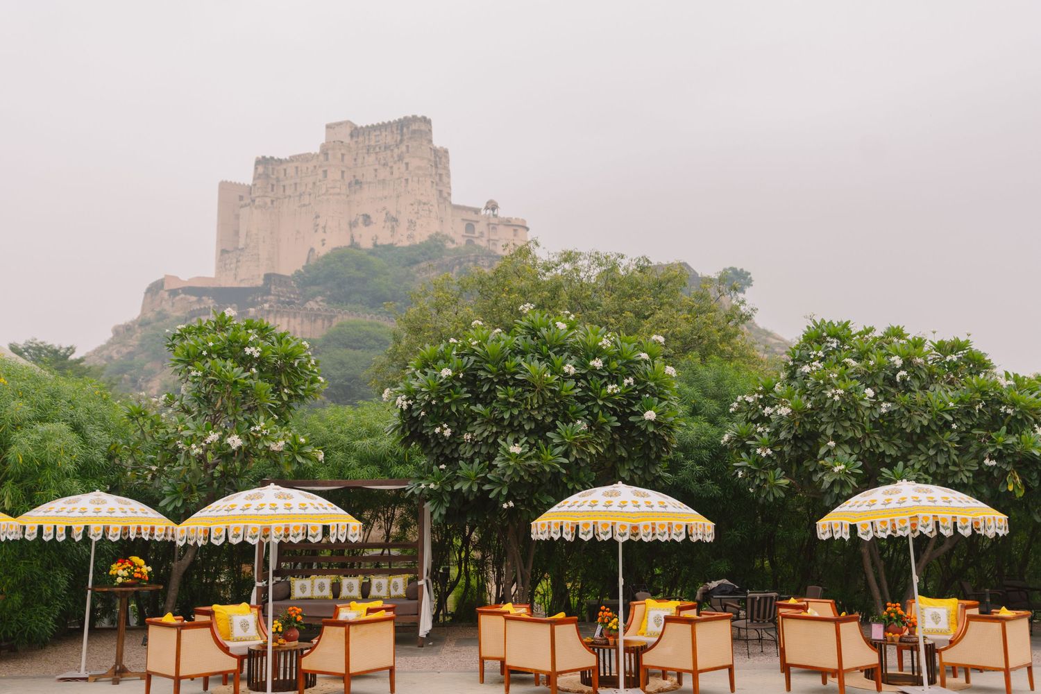 Stone fortress viewed through a row of decorative umbrellas at an outdoor wedding venue.