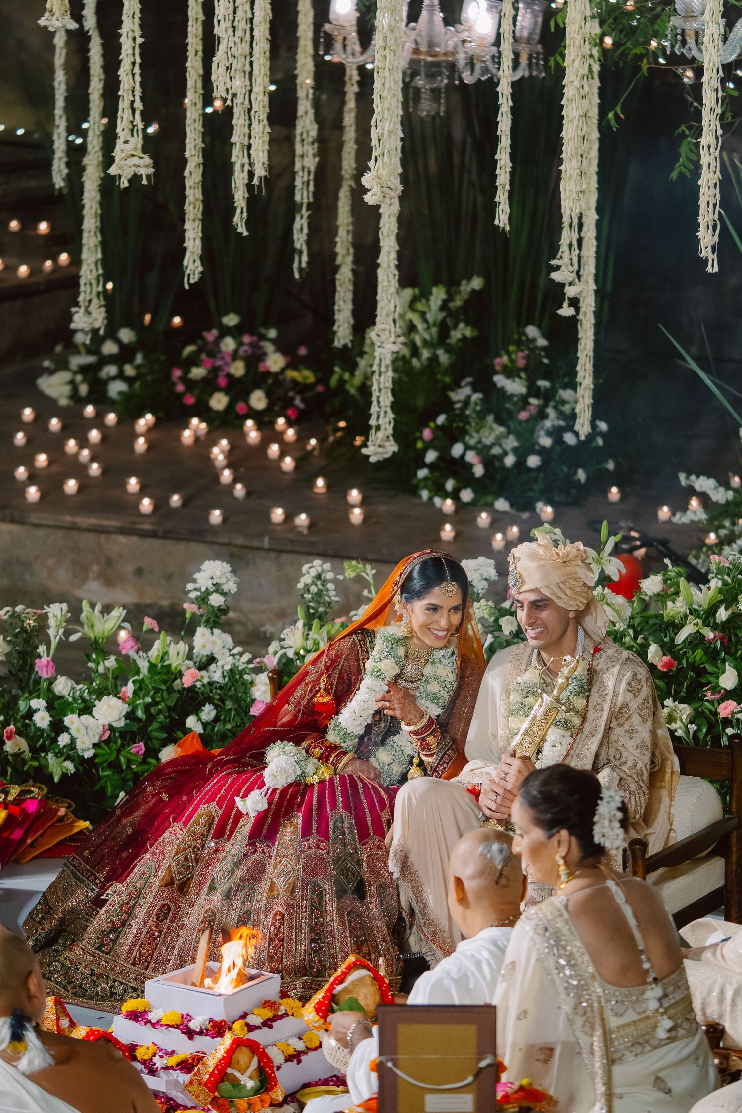 Wedding ceremony with hanging floral garlands and candlelit decorations.
