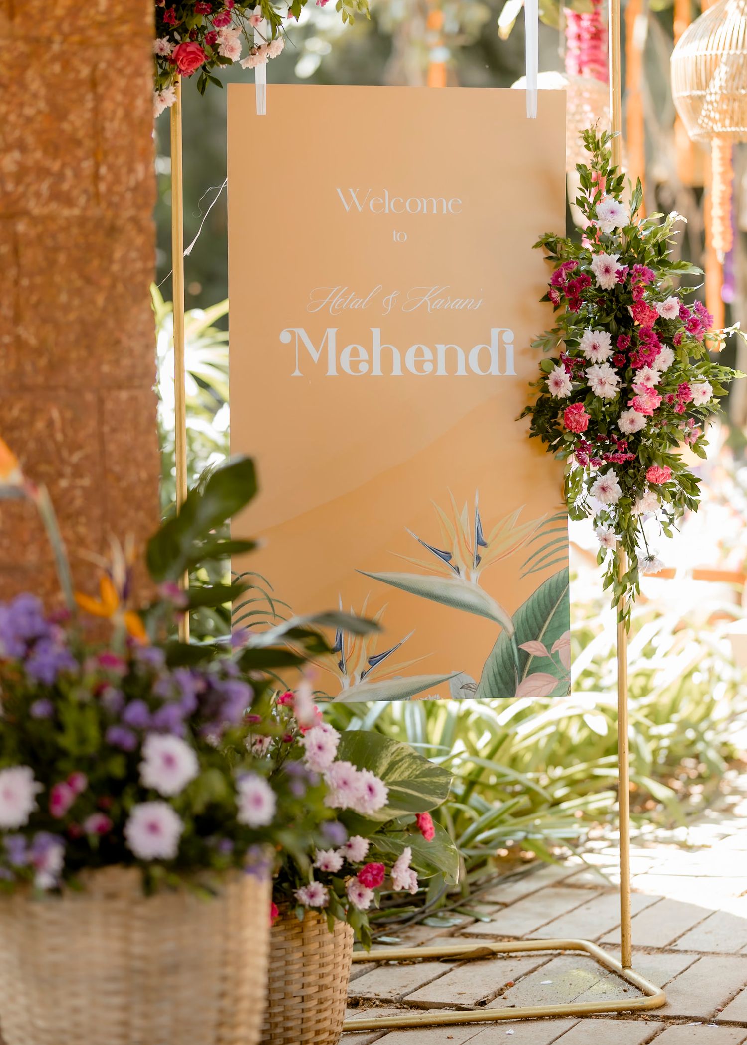 Elegant wedding Mehendi welcome sign in beige with floral decorations and tropical bird of paradise motif.