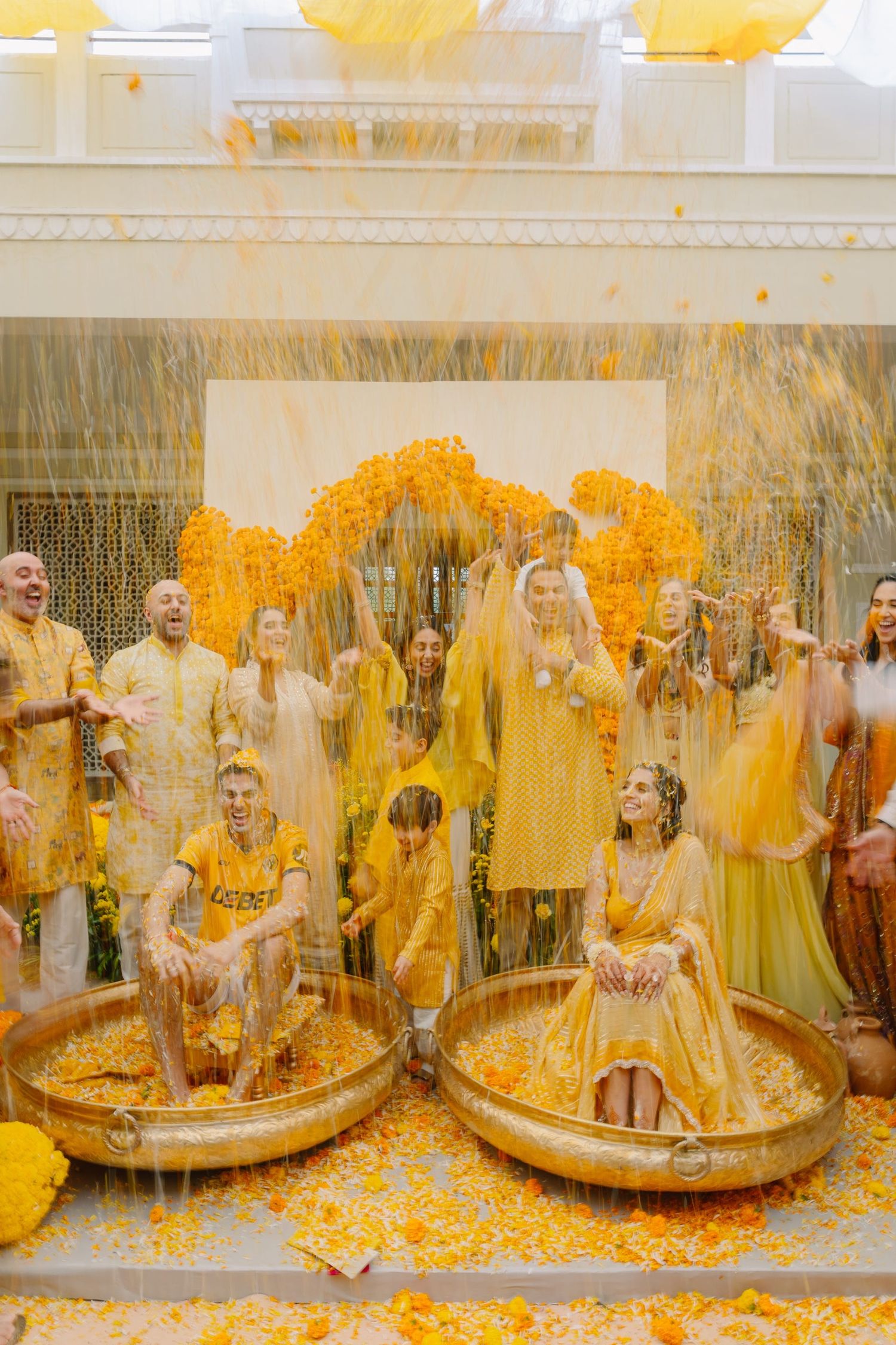Wedding guests celebrate with yellow powder during a vibrant Haldi ceremony.